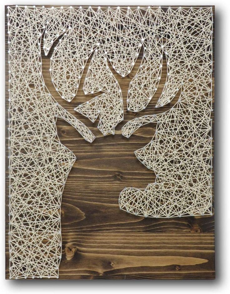 a deer with antlers made out of white yarn on wood paneled wall art