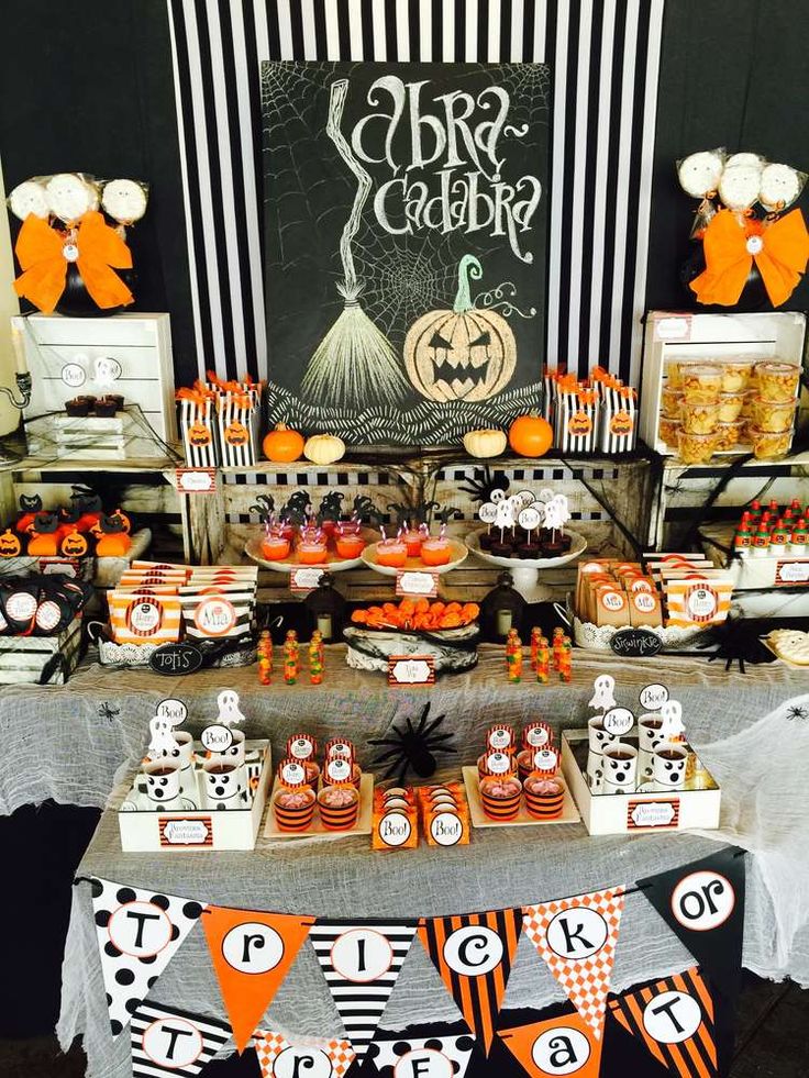 a halloween themed dessert table with orange and black candy bars, cupcakes, and decorations