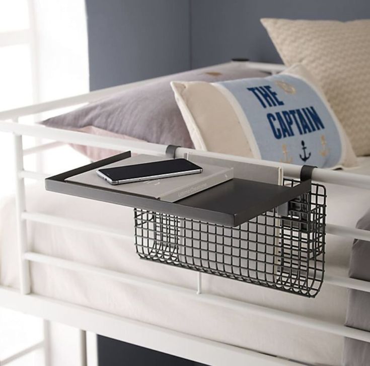 a metal basket on the bottom of a bunk bed with a pillow and other items