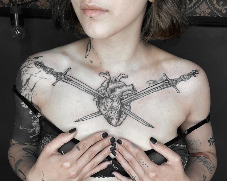 a woman with tattoos on her chest and two swords in the middle of her chest