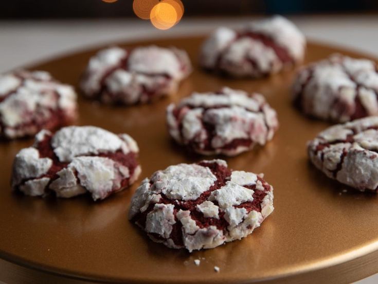 several cookies covered in powdered sugar sit on a wooden platter next to a christmas tree