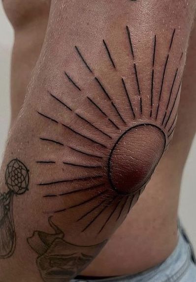 a man with a sun tattoo on his arm