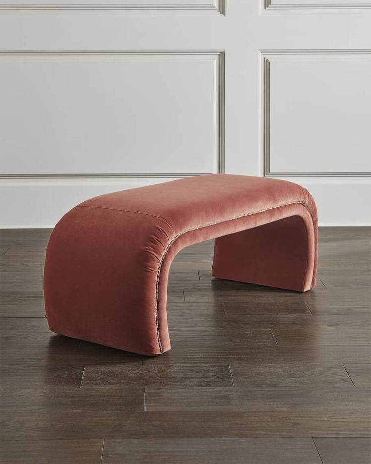 an orange bench sitting on top of a hard wood floor next to a white wall