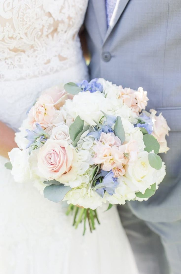 a bride and groom holding a bouquet of white and pink flowers on their wedding day