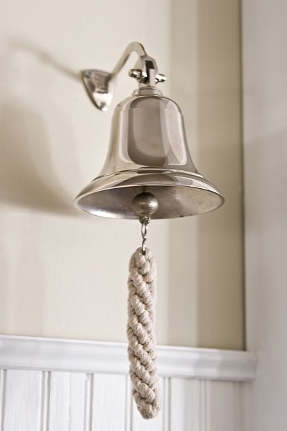 a bell hanging from the side of a wall with a rope on it's end