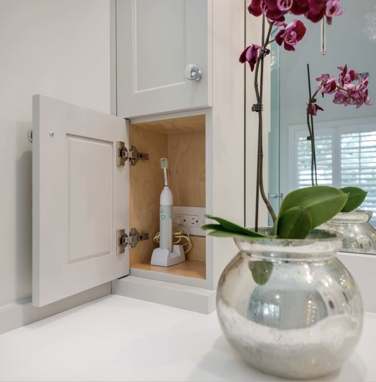 a vase filled with pink flowers sitting on top of a counter next to a mirror