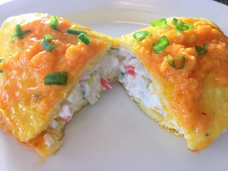 an omelet is cut in half on a white plate with green onions and scallions