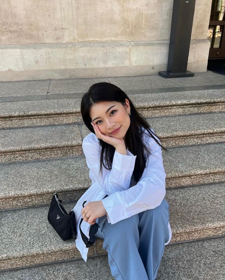 a woman is sitting on the steps with her hand under her chin and looking at the camera