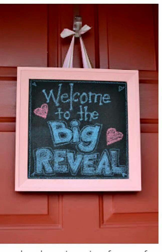 a chalkboard sign hanging on the side of a red door that says welcome to the big reveal