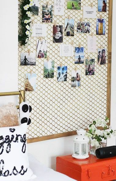 a wall with pictures and magnets on it in a bedroom next to a bed