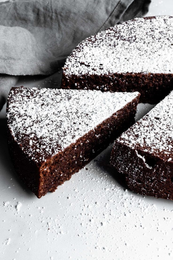 chocolate cake with powdered sugar on top and one slice cut from the other side