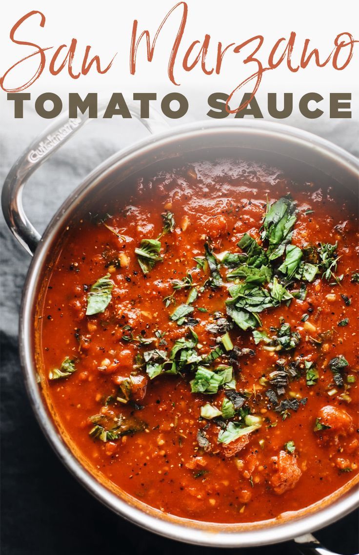 a large pot filled with tomato sauce and garnished with fresh basil on top