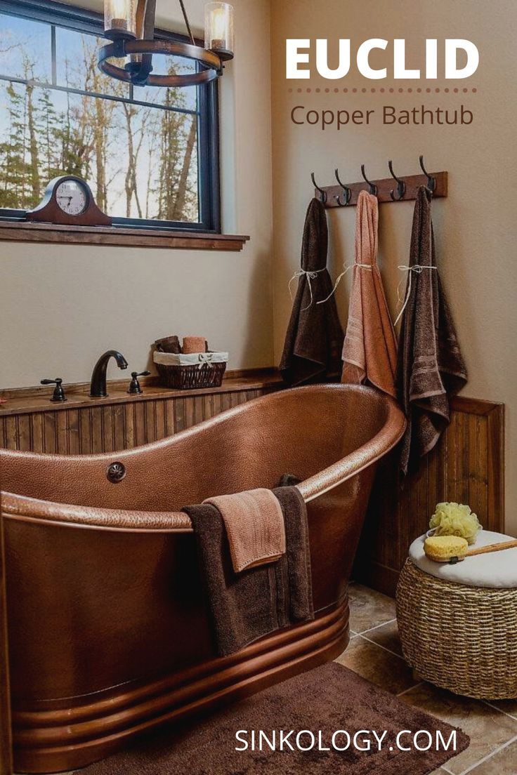 a bath tub sitting next to a window with towels hanging on the side of it