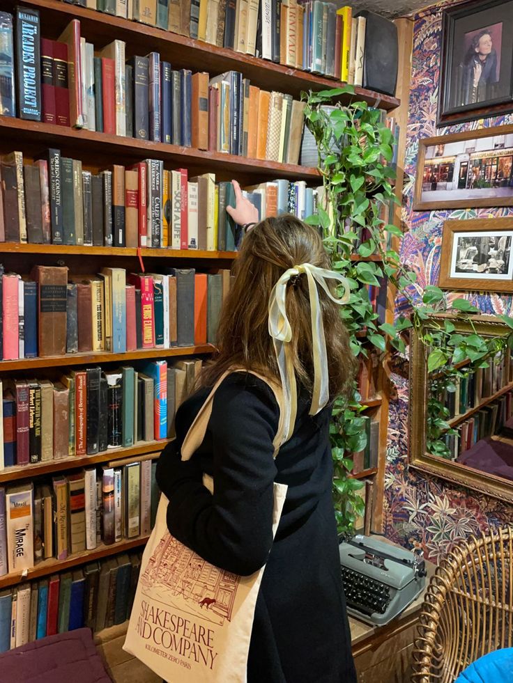 a woman carrying a book bag in front of a bookshelf filled with books