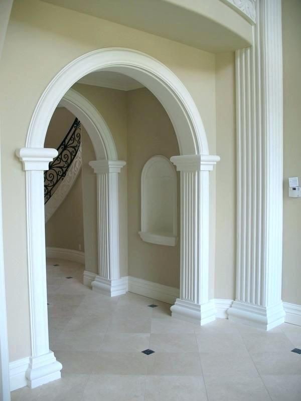 an archway between two white pillars in a room with beige walls and tile flooring