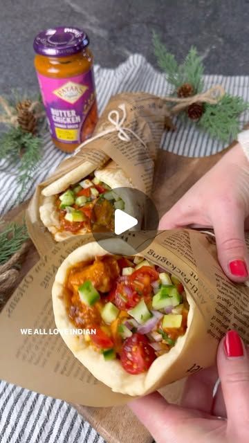 a person is holding an open pita bread with vegetables and meat in it on top of a table