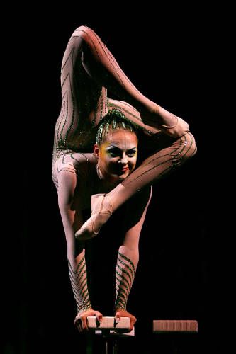 a woman is doing tricks on the balance beam with her hands and legs stretched out