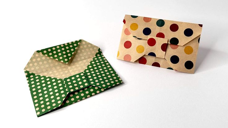 an origami envelope and polka dot paper on a white surface with one folded in half