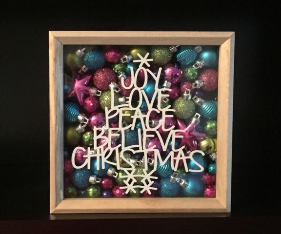 a wooden frame filled with christmas ornaments and the words joy love peace believe christmas written in white