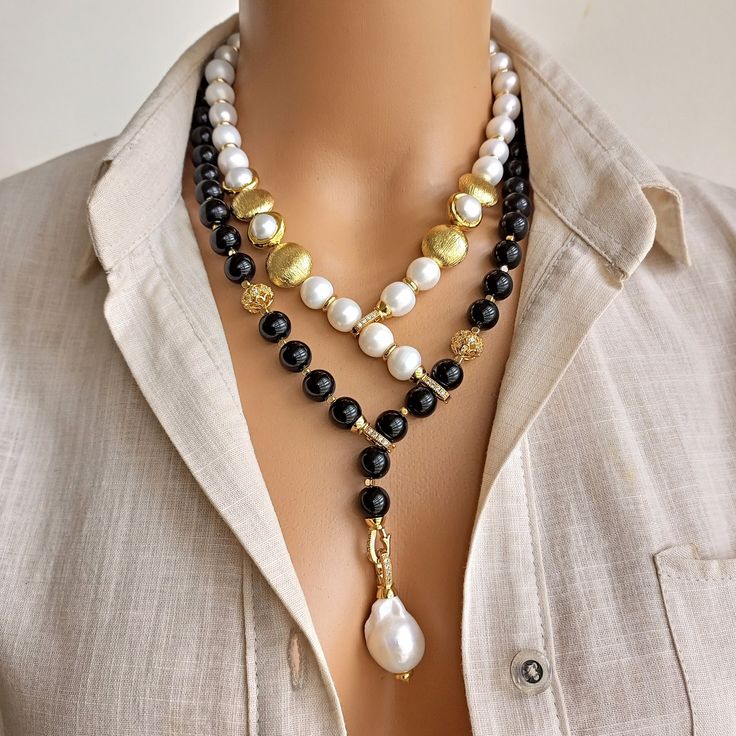 The Pearl and Onyx Beaded Necklace is a true statement accessory that effortlessly combines the beauty of nature with timeless elegance. This stunning piece showcases the striking black tones of genuine Onyx beads, elegantly accented with sparkling premium pearls. Each bead has been meticulously selected to provide a harmonious blend of colors and textures, creating a truly unique and eye-catching design. MATERIALS: - Genuine Onyx Beads: These beads, known for their intense black color and natur Beaded Long Necklace, Diy Statement Necklace, Beautiful Beaded Jewelry, Black Tones, Pearl Necklace Designs, Beaded Necklace Designs, Stone Beaded Necklace, Onyx Necklace, Onyx Bead