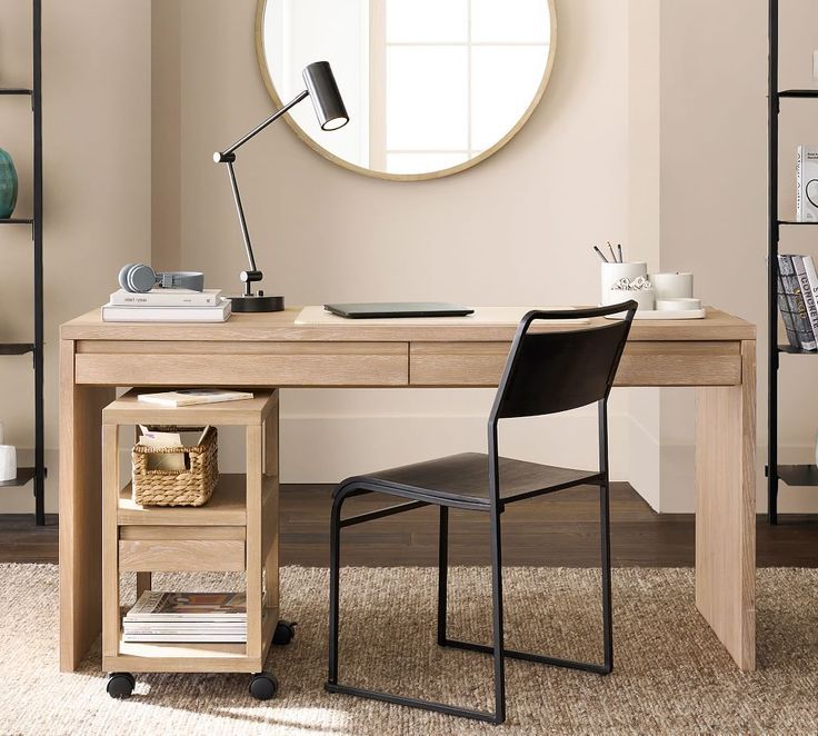 a desk with a chair, lamp and bookshelf in front of a round mirror