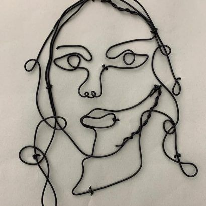 a wire sculpture of a woman's face on a white background with black string