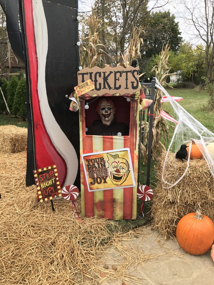 a halloween display with pumpkins, hay and a ticket booth in the middle of it