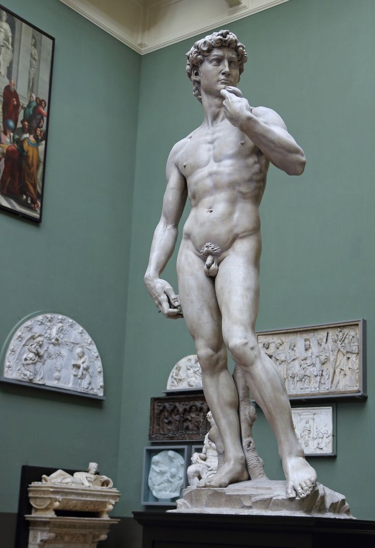 a statue of a man standing in front of some pictures on the wall behind him