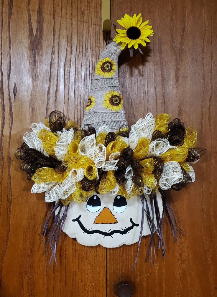 a scarecrow mask with sunflowers on it's head is hanging on the door