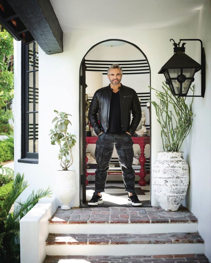 a man standing in the doorway of a house with his hands on his hips and looking at the camera