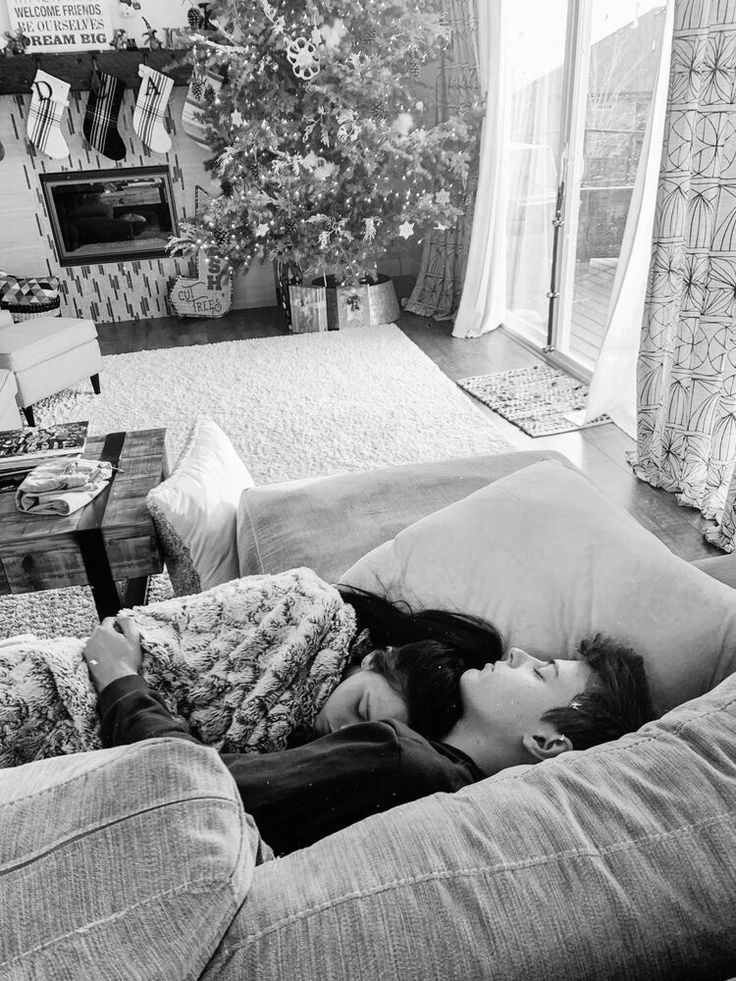 a woman laying on top of a couch next to a man in a living room