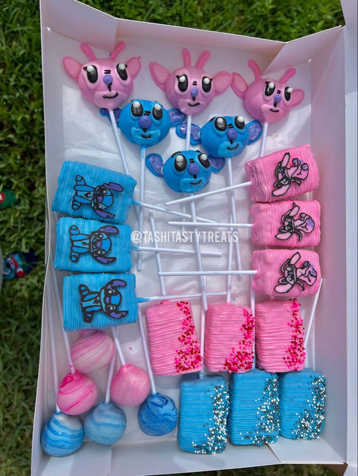 there is a box filled with cake pops and candies in the shape of cartoon characters