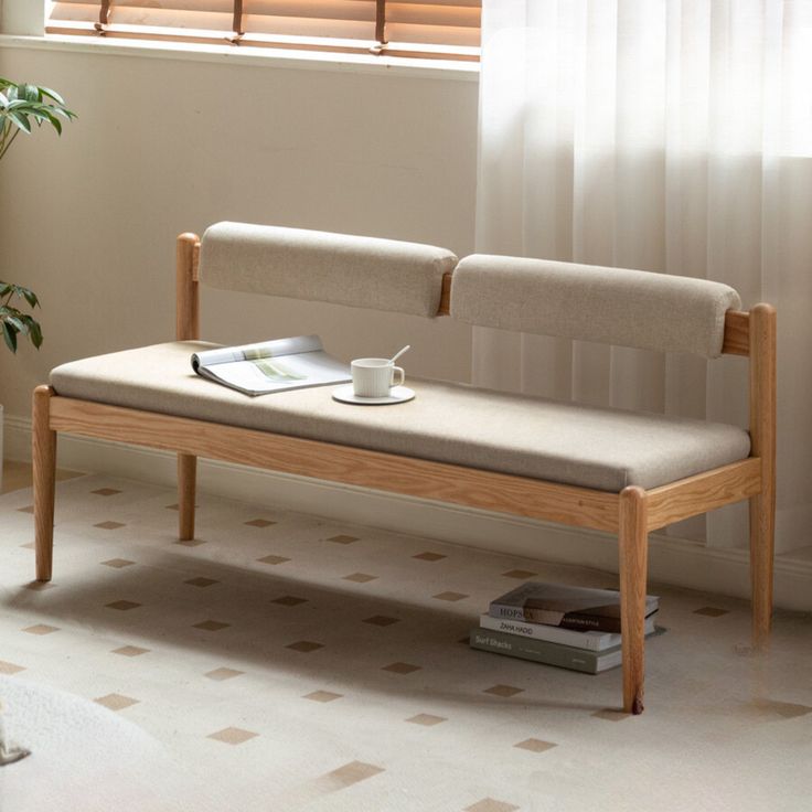 a wooden bench sitting in front of a window next to a potted plant and book