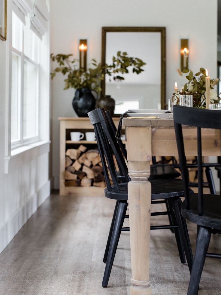 a dining room table with black chairs and a mirror