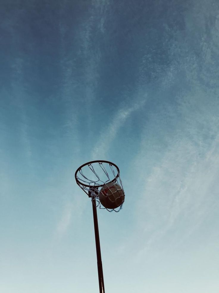 a basketball hoop in the middle of a clear blue sky with wispy clouds