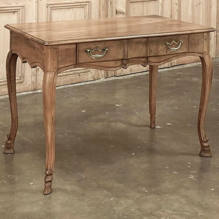 an old wooden table with two drawers and one drawer on the top, in front of a wall