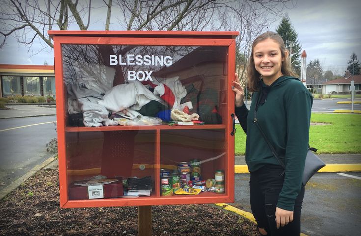 a woman standing in front of a blessing box