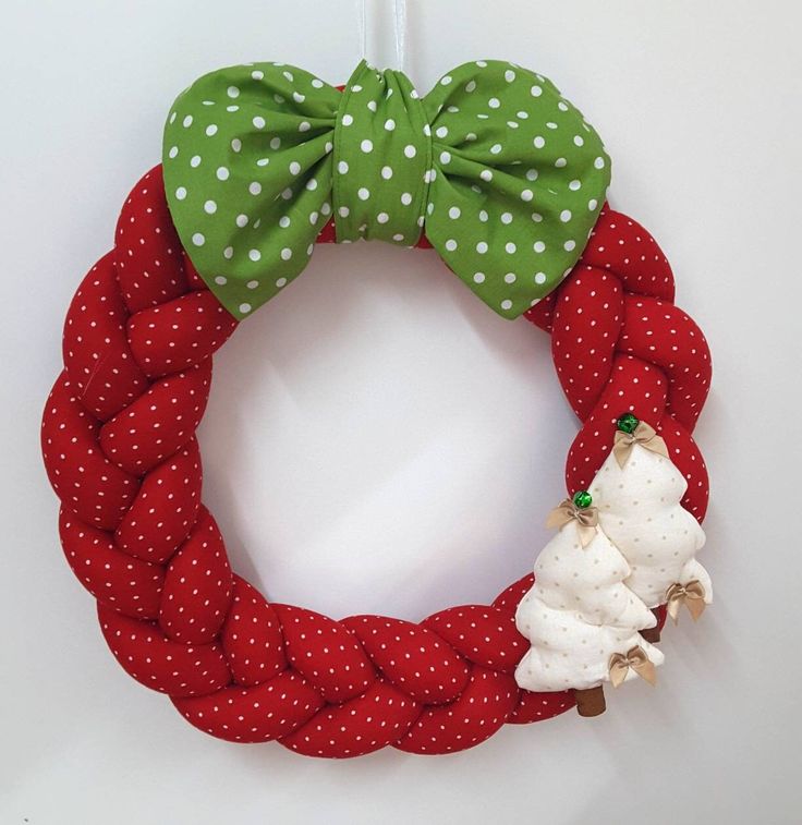 a red and green christmas wreath with two white poodles hanging from it's side