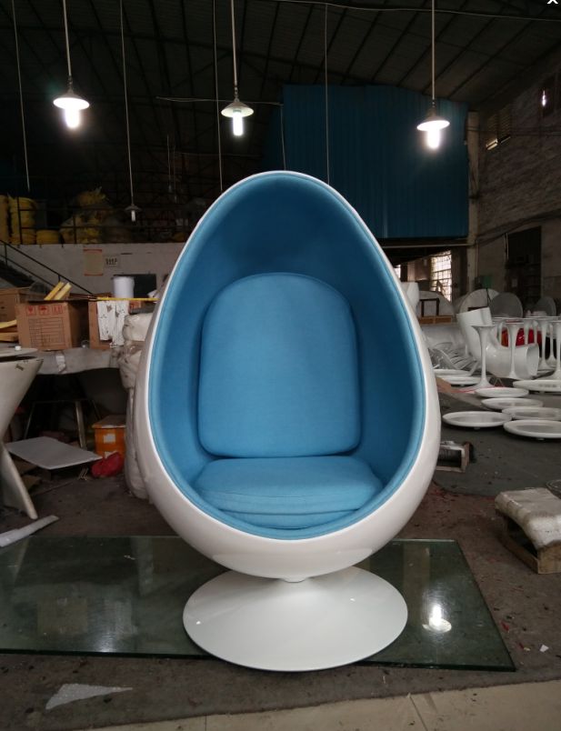 a blue and white egg chair sitting on top of a glass table in a room