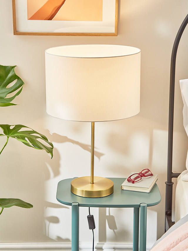 a lamp on a table next to a bed