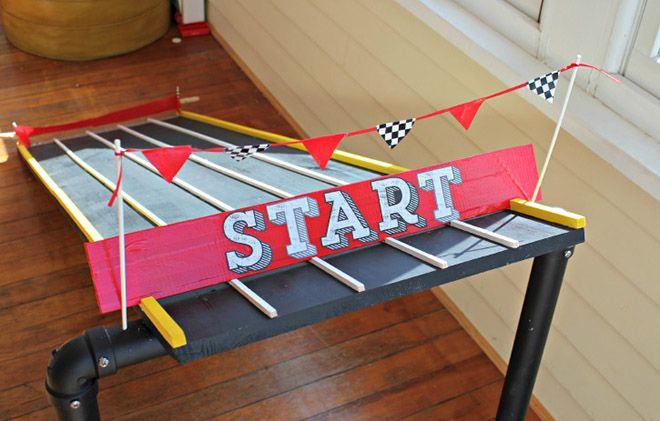 a wooden sign that says start sitting on top of a black and red table with flags