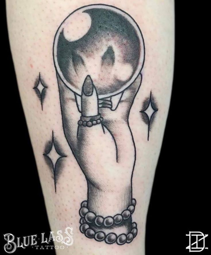 a black and white image of a hand holding a ball with stars around it on the leg