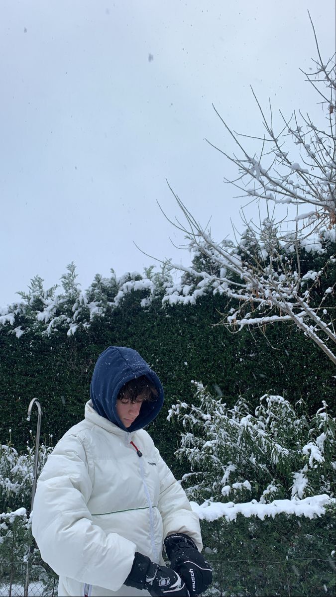 a person sitting in the snow with their skis on and wearing a white jacket