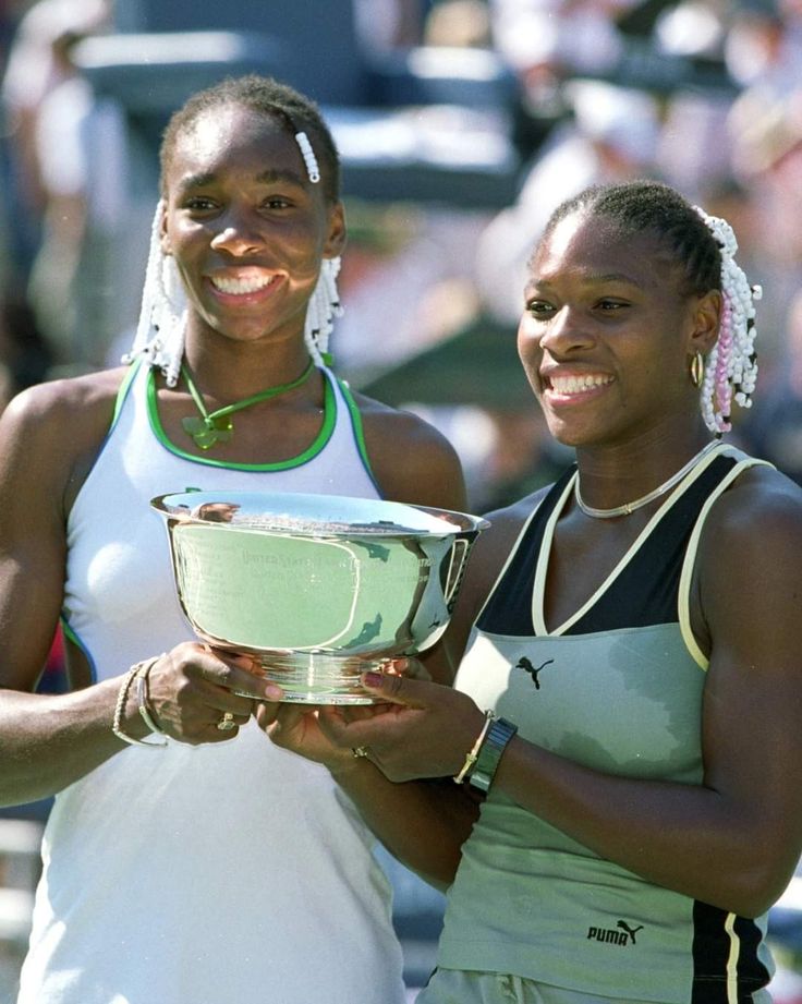 two female tennis players pose with their trophy