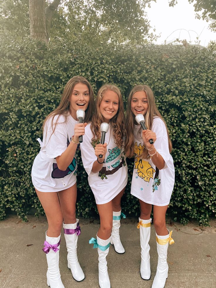 three girls dressed in white holding up microphones