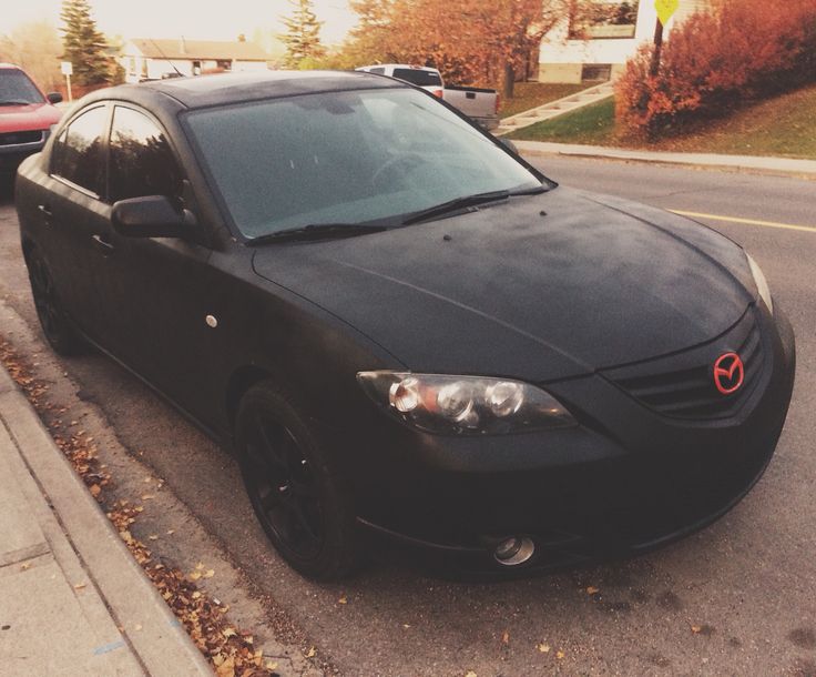 a black car is parked on the side of the road