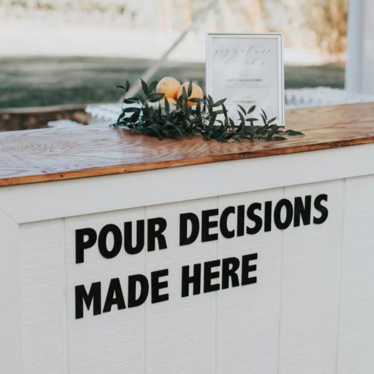 a sign that says four decision made here on the side of a white building with oranges and greenery