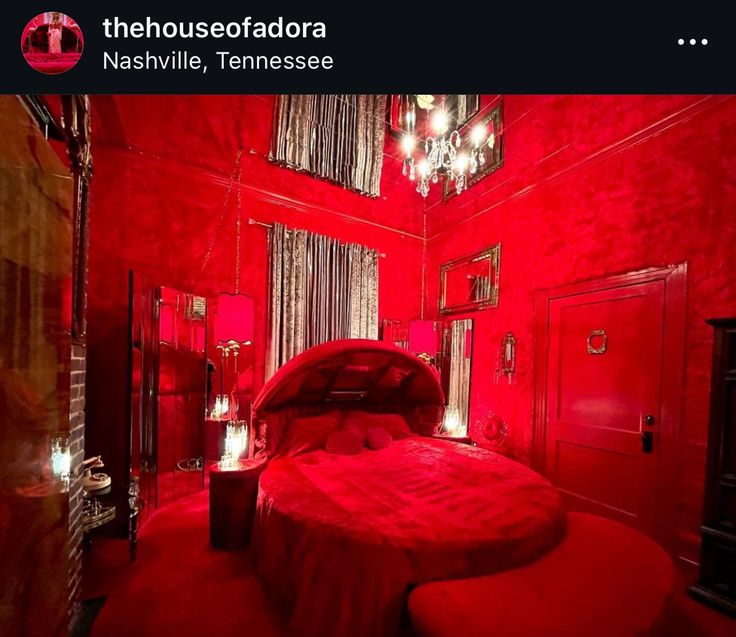 a red room with a bed and chandelier hanging from it's ceiling