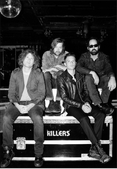 black and white photograph of four men sitting on a stage with disco balls in the background