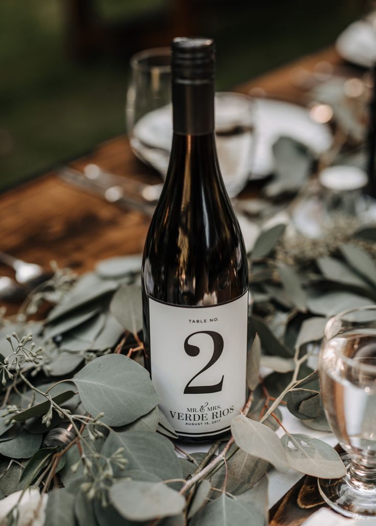 a bottle of wine sitting on top of a table next to glasses and silverware